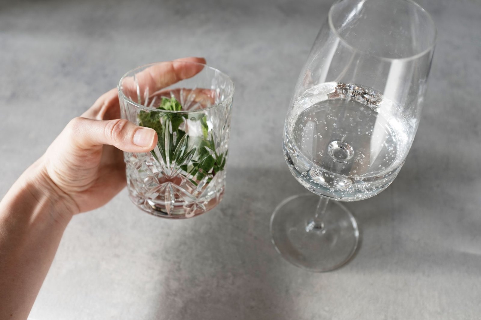 A photo of a refreshing glass of basil infused water with fruits and herbs